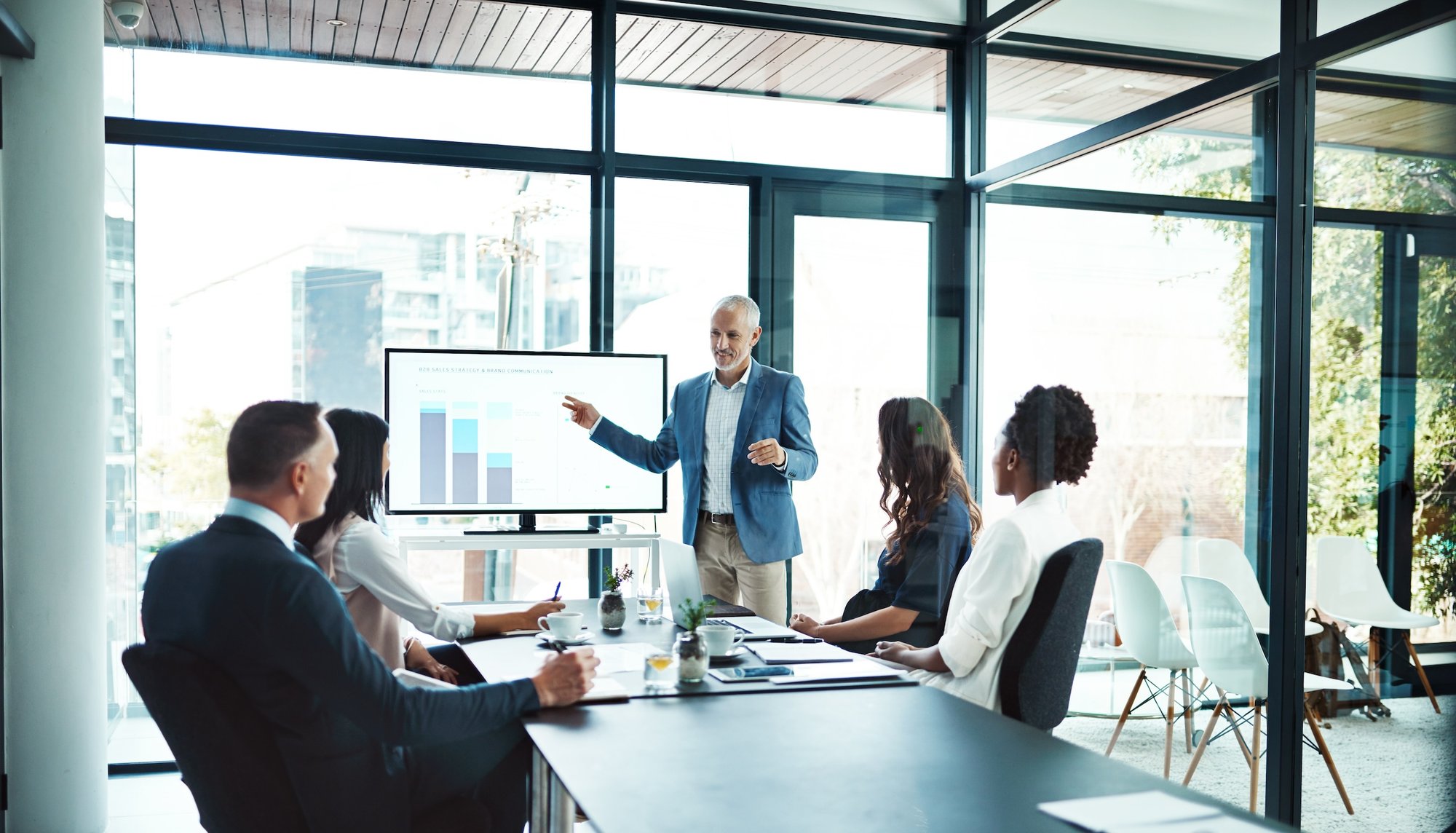 Business meeting with presenter pointing to bar chart